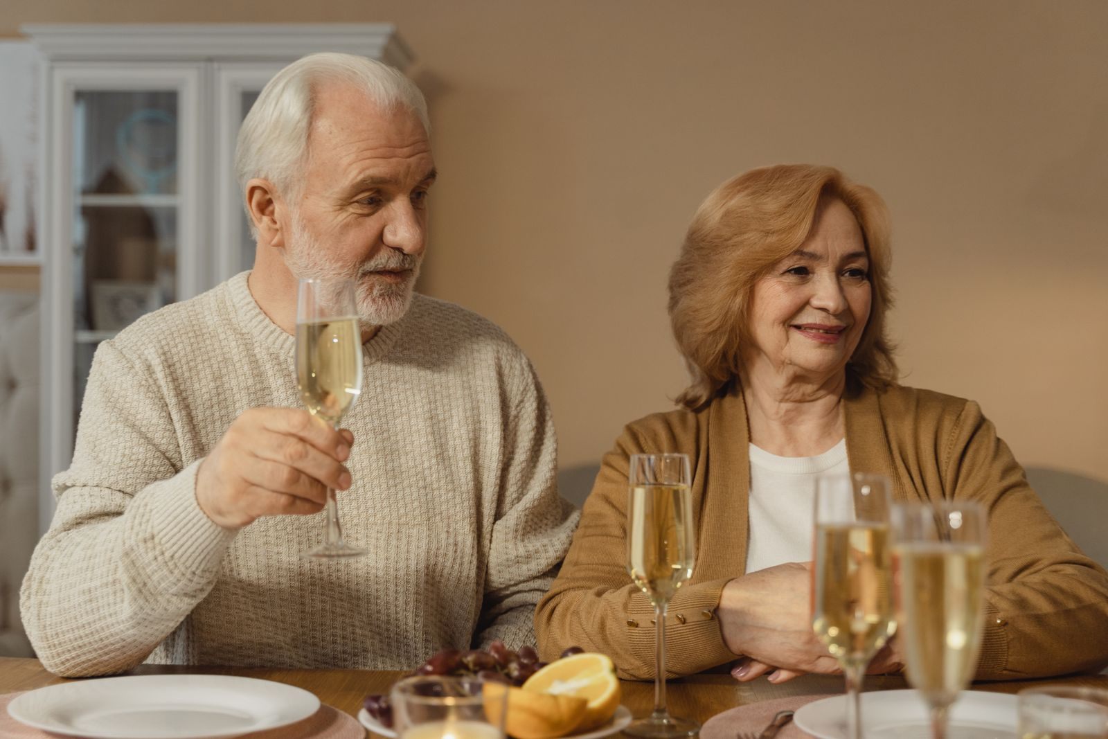 Older couple toasting with champagne at a celebration dinner, as on a 50th wedding anniversary cruise